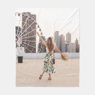 Woman in white and blue floral dress holding hat fleece blanket