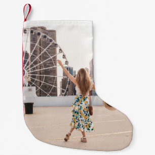 Woman in white and blue floral dress holding hat small christmas stocking