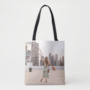 Woman in white and blue floral dress holding hat tote bag