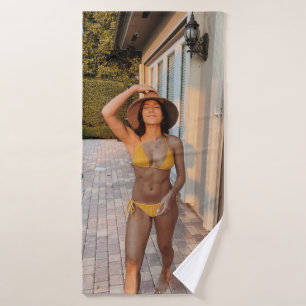 Woman in yellow bikini standing on brown brick flo bath towel