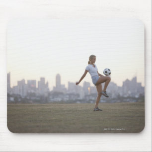 Woman kneeing soccer ball in urban park mouse mat