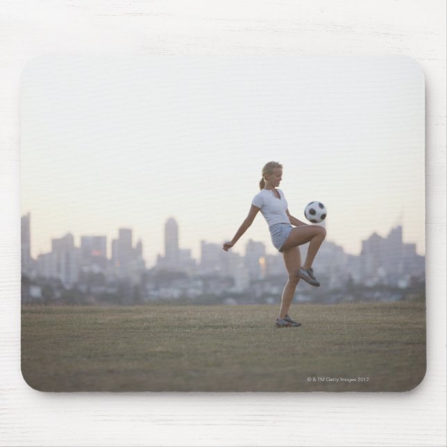Woman kneeing soccer ball in urban park mouse mat (Front)