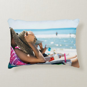 Woman lying on sun lounger covering her face with  decorative cushion