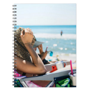 Woman lying on sun lounger covering her face with notebook