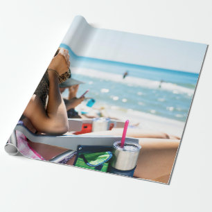 Woman lying on sun lounger covering her face with wrapping paper