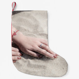 Woman lying on white sand small christmas stocking