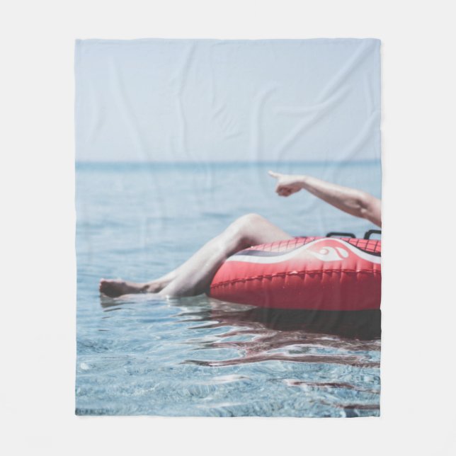 Woman on an inflatable float in the ocean pointing fleece blanket (Front)