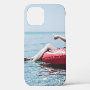 Woman on an inflatable float in the ocean pointing iPhone 12 case