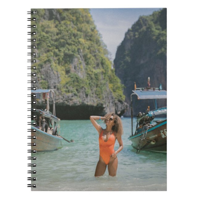 Woman on body of water between brown boats notebook (Front)