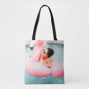 Woman on pink inflatable flamingo on outdoor pool tote bag