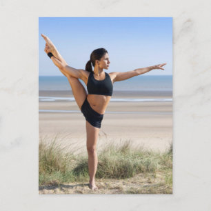 woman practicing yoga on beach wearing postcard