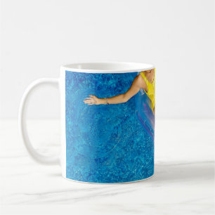 Woman riding on plastic floating buoy on body of w coffee mug