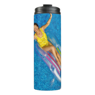 Woman riding on plastic floating buoy on body of w thermal tumbler