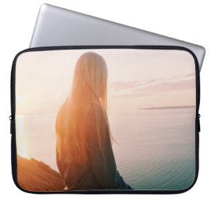 Woman stands near body of water during golden hour laptop sleeve