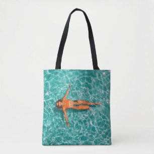 Woman swimming alone in body of water tote bag