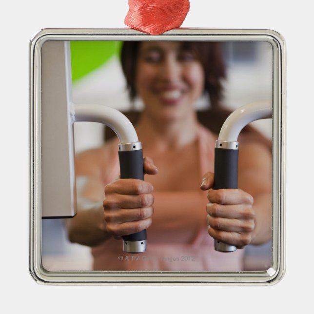 Woman using exercise machine in gym metal tree decoration (Front)