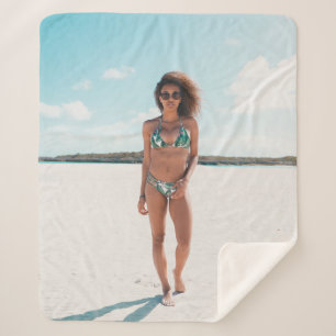 Woman wearing bikini standing on sand sherpa blanket