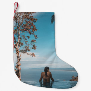 Woman wearing black bikini tap swimming on body of small christmas stocking