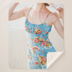 Woman wearing blue floral rompers and brown hat sherpa blanket
