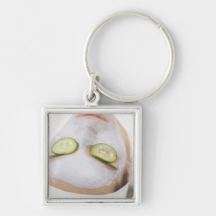 Woman with face mask and cucumber slices on key ring