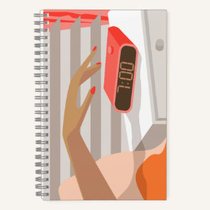Womans hand pushing on alarm clock snooze button notebook