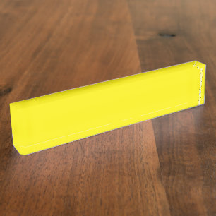 Yellow and orange abstract shapes overlap on a pla nameplate