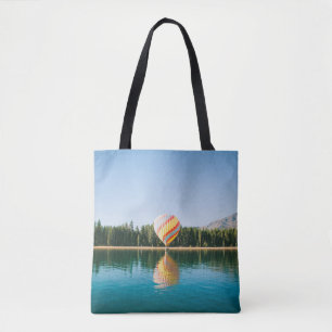 Yellow, red, and blue hot air balloon near trees a tote bag