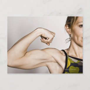 Young blond female flexes bicep muscle while postcard