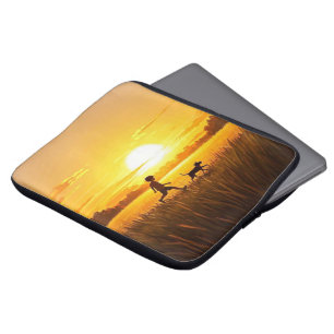 Young boy running with dog at sunset laptop sleeve
