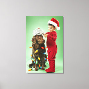 Young boy wrapping Christmas lights around a dog Canvas Print