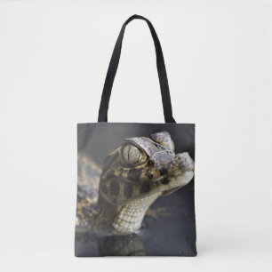 Young cayman in water with reflection tote bag