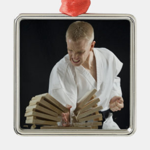 Young man breaking boards with karate chop on metal tree decoration