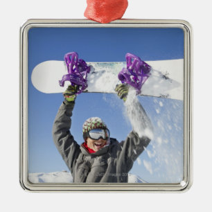 Young man holding his snowboard above his head metal tree decoration