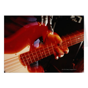 Young man playing bass guitar, close-up of hand