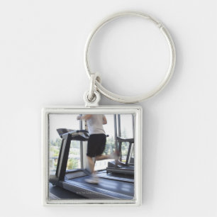 Young man running on a treadmill at health club, key ring
