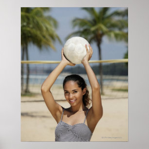 Young woman holding volleyball and smiling at poster
