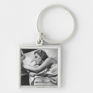 Young woman lying on bed turning off lamp on key ring